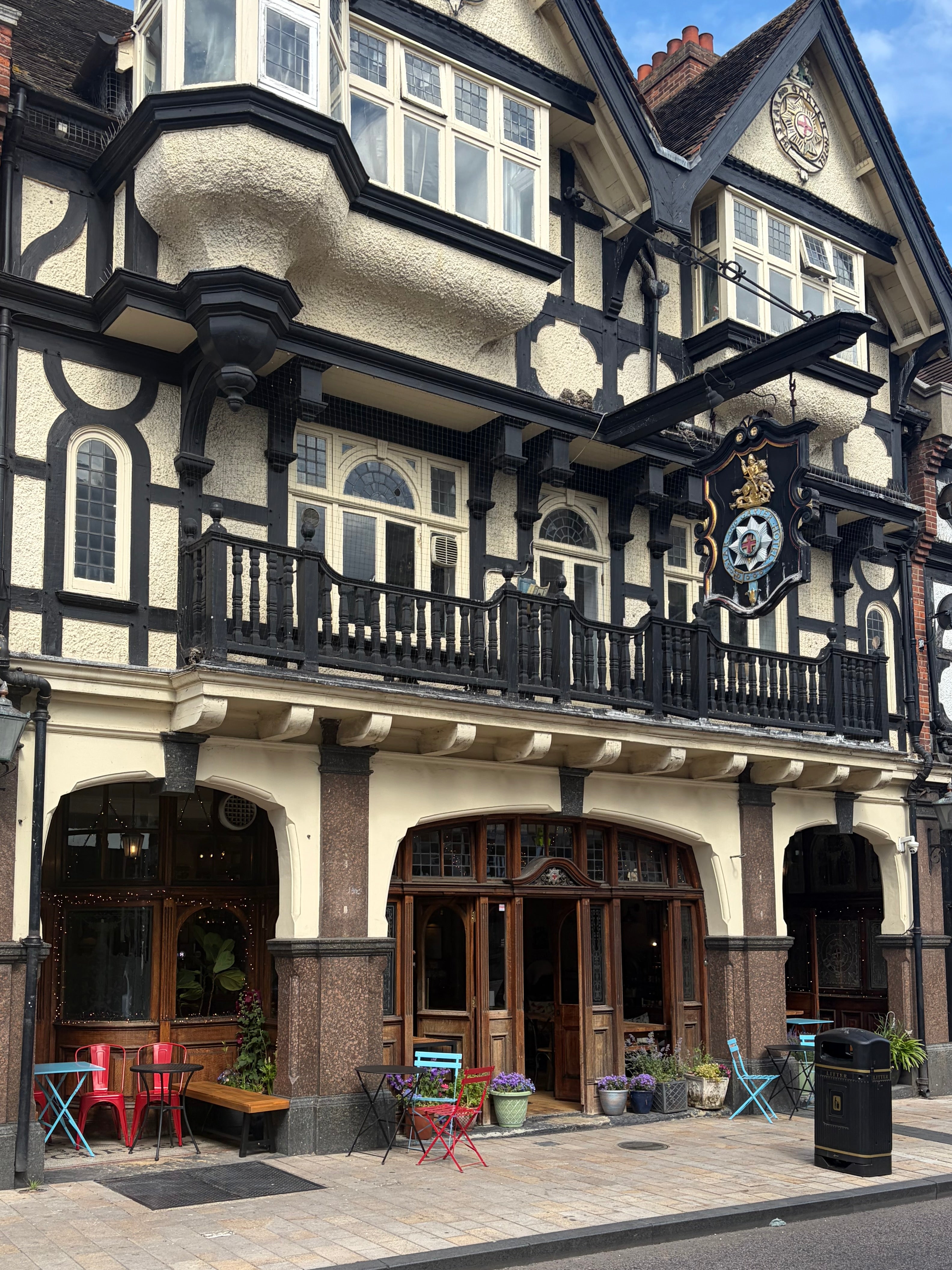 Traditional English pub with decorative facade and outdoor seating area.